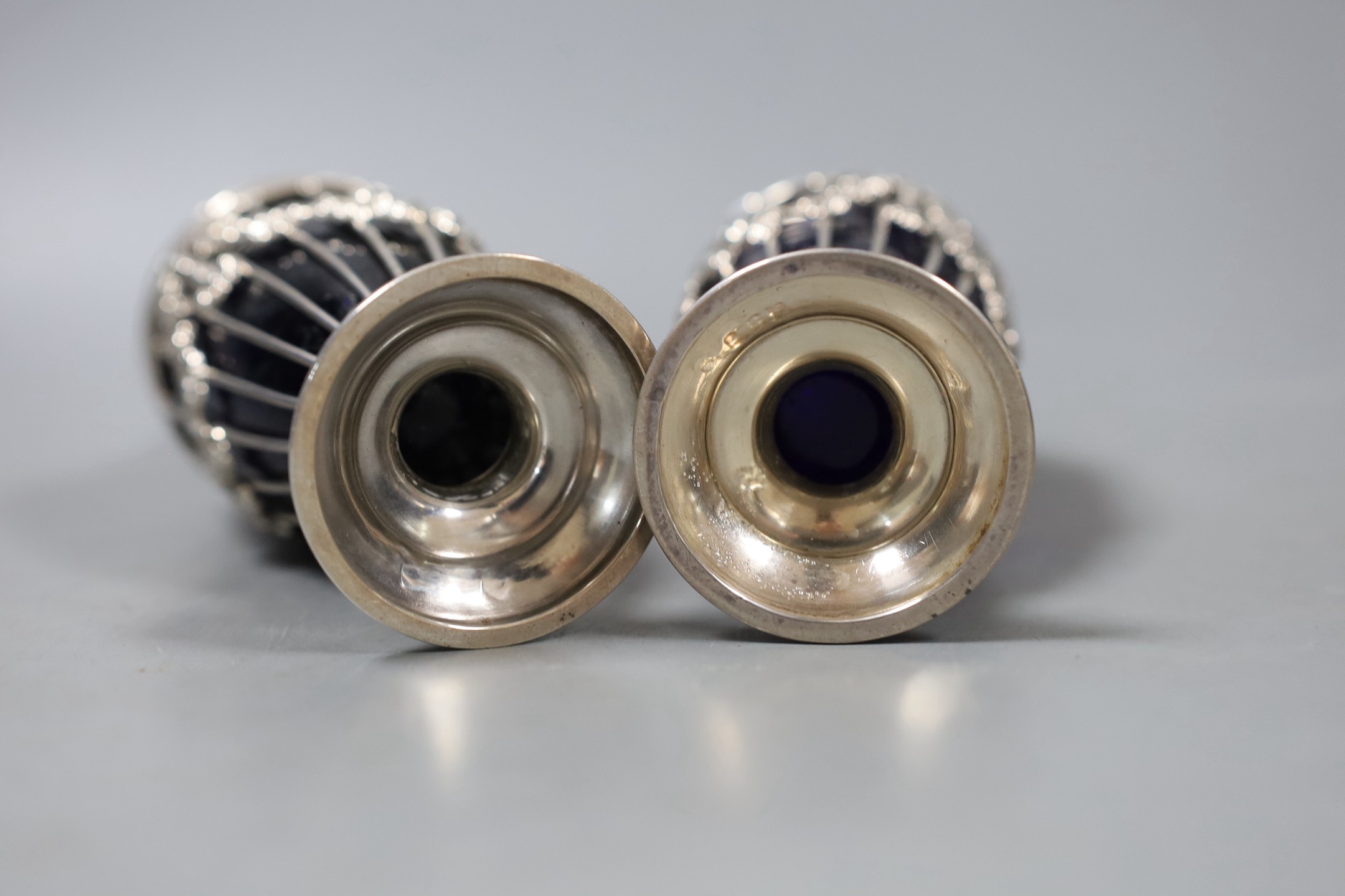 A pair of George V pierced silver sugar sifters, with blue glass liners, London, 1912, height 17.9cm.